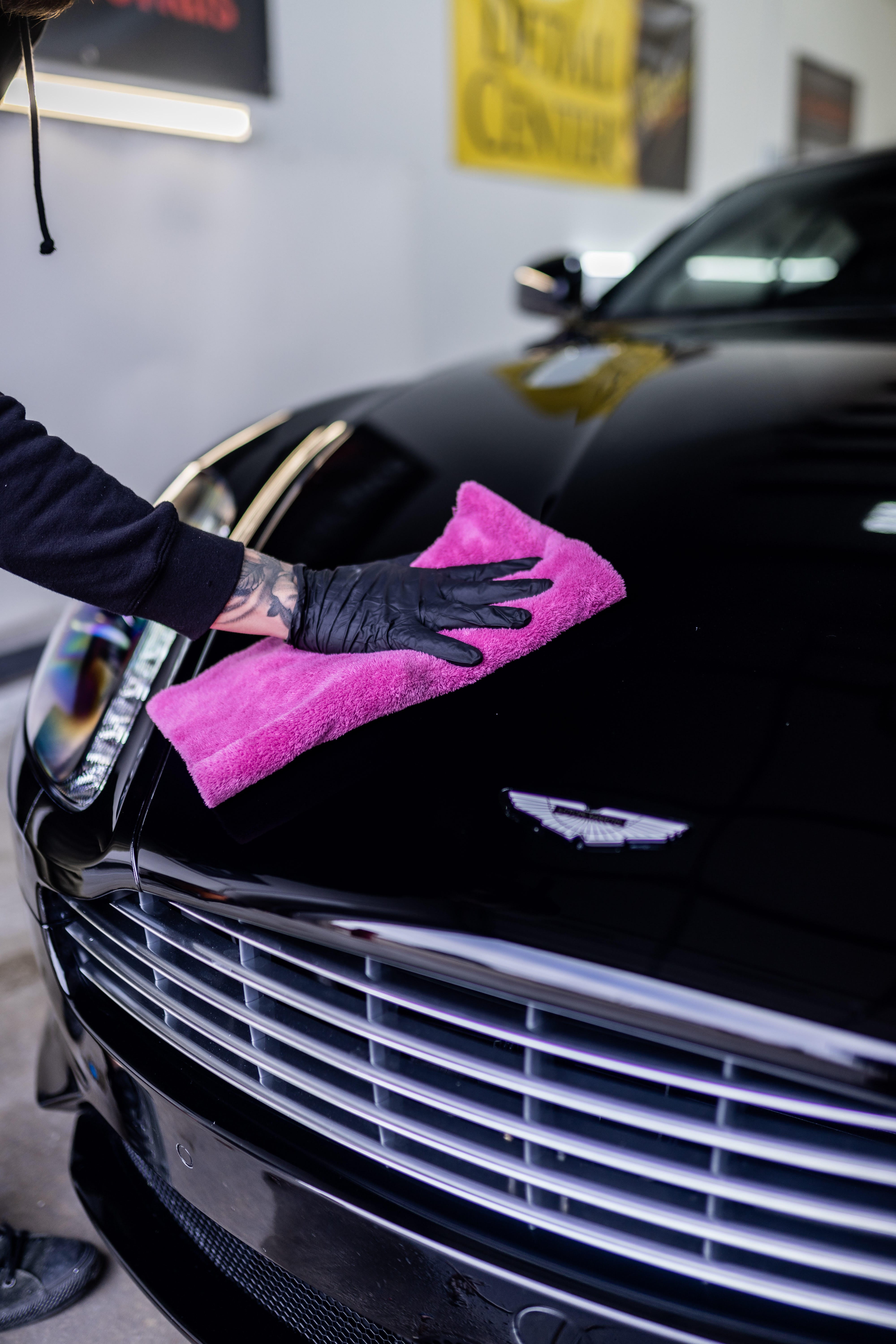 Person wiping down car hood after ceramic coating process.