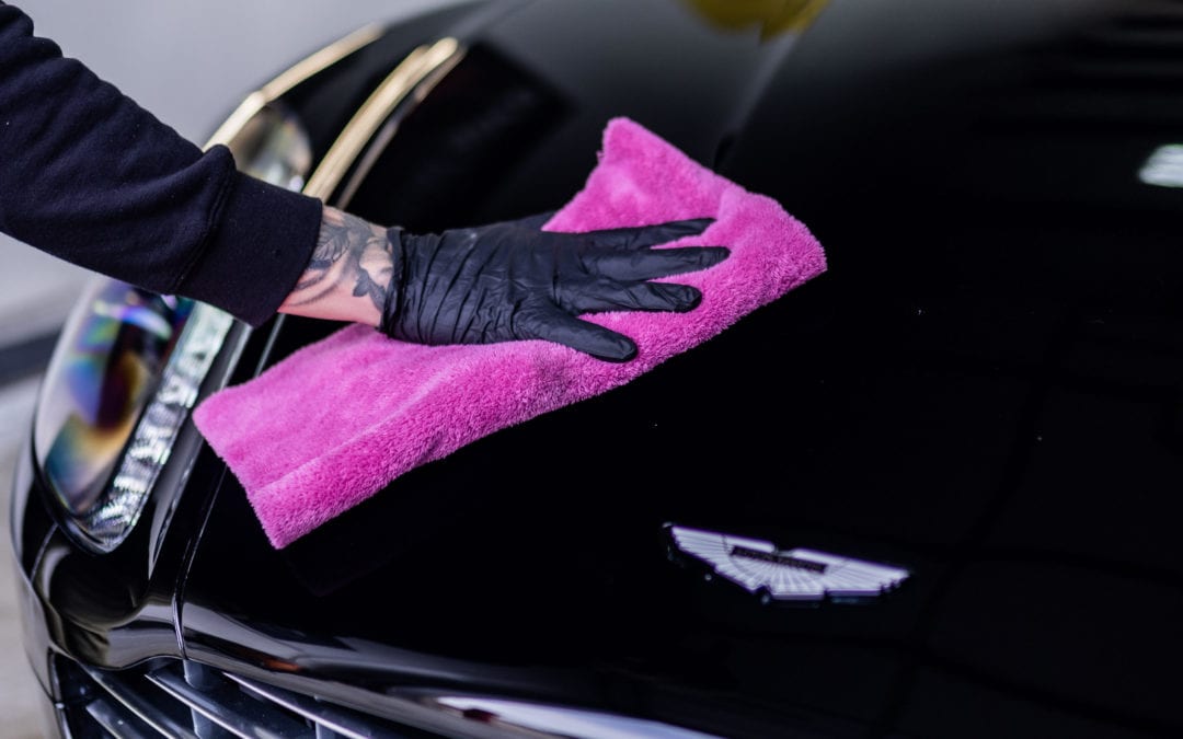 Person wiping down car hood after ceramic coating process.